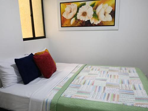 a bed with a quilt and a picture on the wall at Acogedor Apartamento in Ibagué