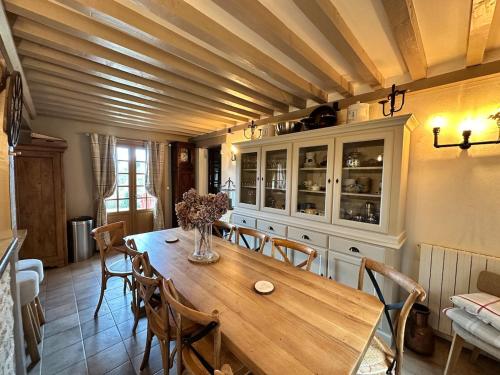 een eetkamer met een houten tafel en stoelen bij La Moutinière, luxury cottage with pool in Manerbe