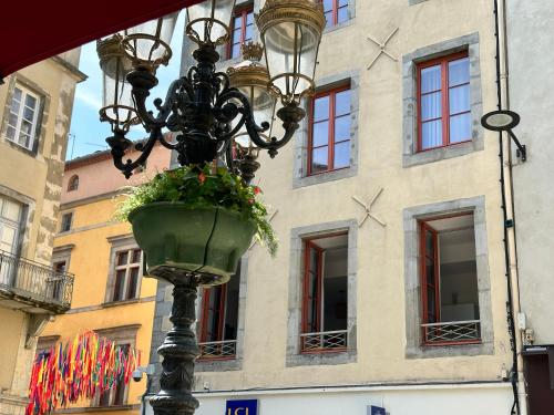 a street light with a flower pot on it in front of a building at La magie de Carnot Meublé de tourisme 3 étoiles in Carcassonne