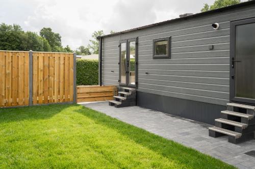 a small house with a fence and a yard at Nieuw chalet Zeeland met omheinde tuin & airco nabij natuur en zwembad VP089 in Heinkensand