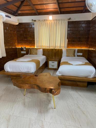 a bedroom with two beds and a wooden table at Love Green Resorts in Palladam
