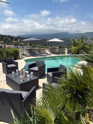 une piscine avec des chaises noires et une table avec une table dans l'établissement LA BASTIDE DE CHARME, à Vence