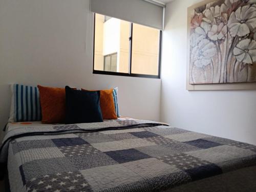 a bedroom with a bed with a quilt on it at Acogedor Apartamento in Ibagué