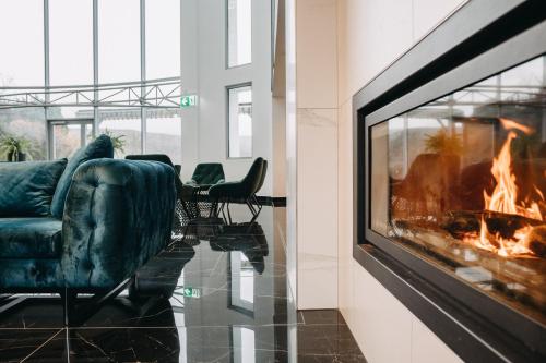 a living room with a fireplace and a couch at Hotel Ózon & Luxury Villas in Mátraháza