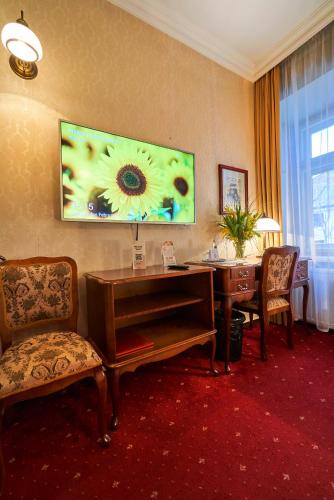 a hotel room with a desk and a tv on the wall at Pollera in Kraków