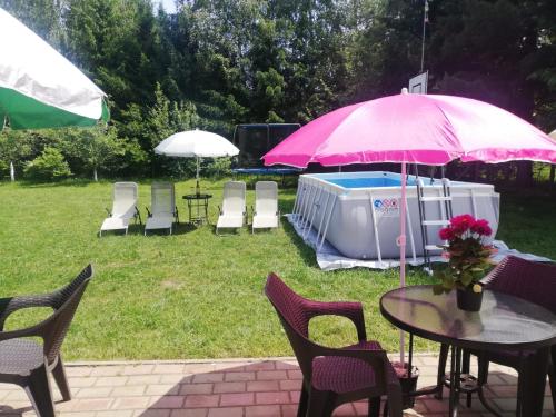a table and chairs with a pink umbrella and a pool at Vila Roberta Breaza ,BV in Breaza