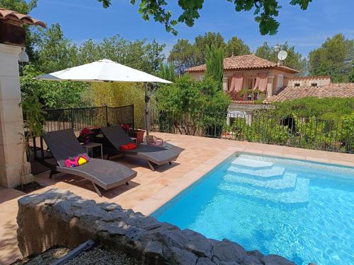 une piscine avec deux chaises et un parasol dans l'établissement Entre Vignes & Piano 