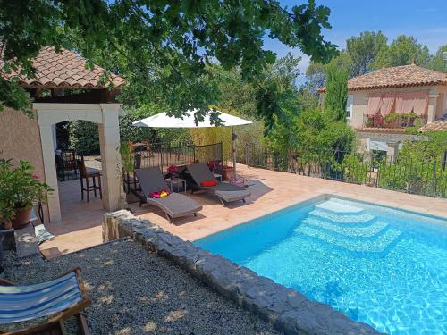une piscine avec deux chaises longues et un parasol dans l'établissement Entre vignes & Piano 