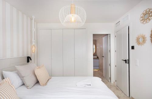 a bedroom with a white bed and a chandelier at CC8 III by ZANIS in Torrevieja