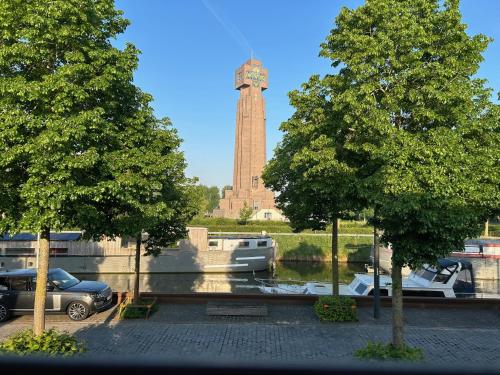 a clock tower with a car parked in a parking lot at Villa Couleur in Diksmuide