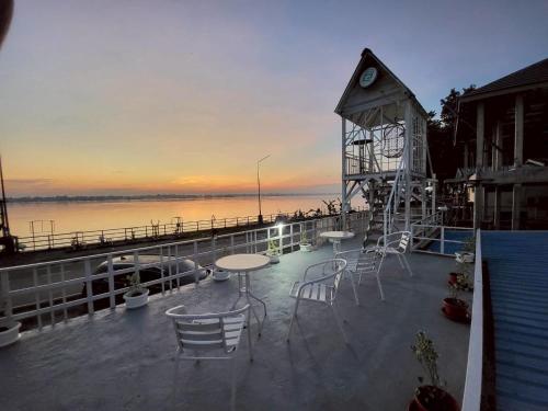 a clock tower sitting on top of a deck with chairs at Aran hostel Spa&Cafe Riverside That Phanom in Amphoe That Phanom