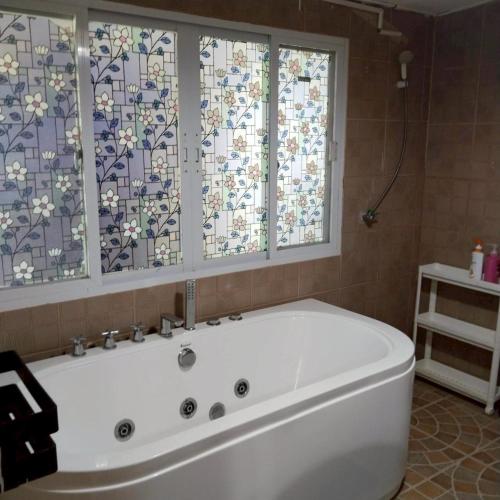 a white bath tub in a bathroom with windows at Aran hostel Spa&Cafe Riverside That Phanom in Amphoe That Phanom