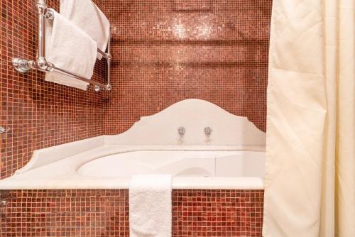 a bath tub in a tiled bathroom with a sink at Relais Villa San Martino in Martina Franca