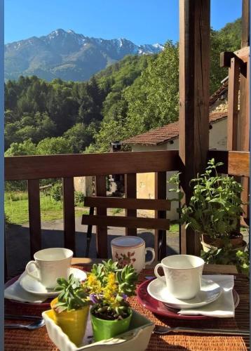 a table with plates and cups and plants on a balcony at B&B Alla Borgata in Boves