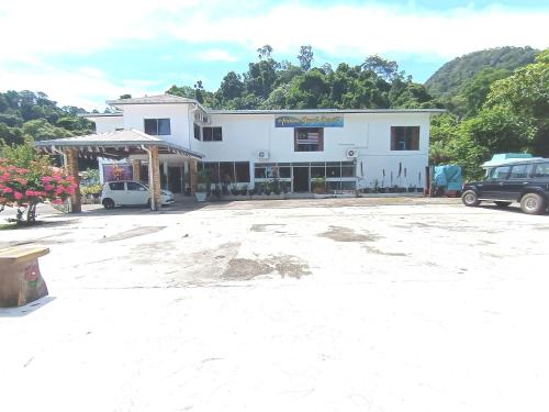 a white building with cars parked in a parking lot at Analisa Beach Resort in Pangkor