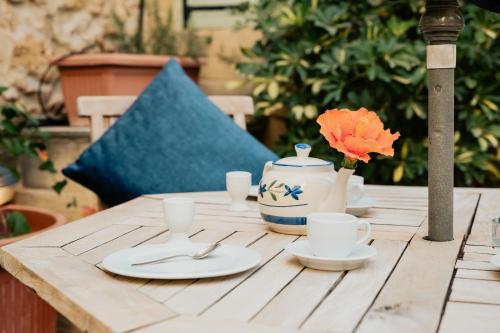 a wooden table with plates and a vase on it at Mohba Townhouse, Private Roof Top Jacuzzi, Garden, BBQ by Haven & Keys Malta in Xagħra