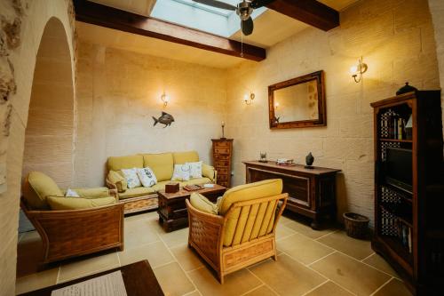 a living room with a couch and a table at Mohba Townhouse, Private Roof Top Jacuzzi, Garden, BBQ by Haven & Keys Malta in Xagħra