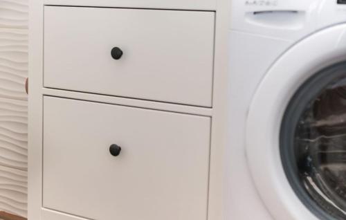 a laundry room with white cabinets and a washing machine at House Victoria 2 by Villas Guide in Nerezine