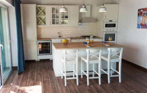 a kitchen with white cabinets and a wooden island with bar stools at House Victoria 2 by Villas Guide in Nerezine