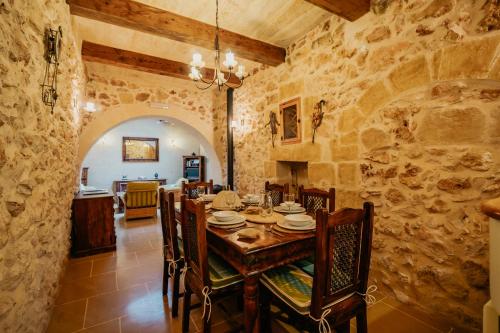a dining room with a table and chairs in a building at Mohba Townhouse, Private Roof Top Jacuzzi, Garden, BBQ by Haven & Keys Malta in Xagħra