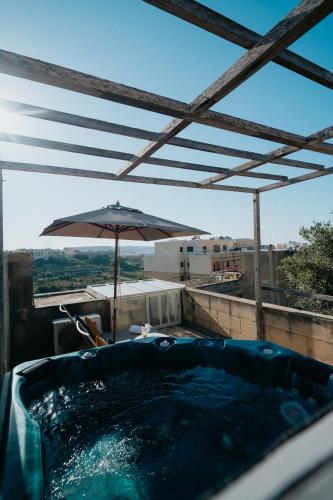 a hot tub with an umbrella on top of a building at Mohba Townhouse, Private Roof Top Jacuzzi, Garden, BBQ by Haven & Keys Malta in Xagħra