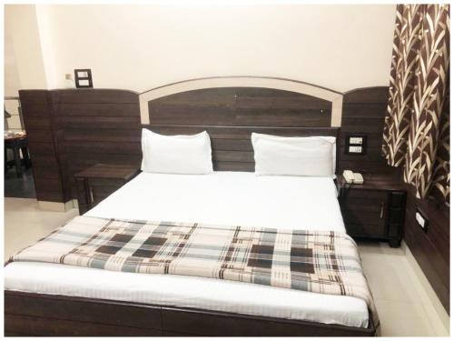 a bedroom with a large bed with a wooden headboard at HOTEL G!S Paradise Amritsar - Provided Fully Air Conditioned & Well Decorated Rooms - Free Parking And Free Wi-fi Facility - A Premium Hotel In Amritsar in Amritsar