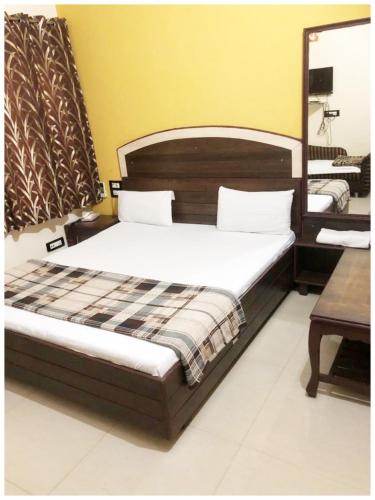 a bedroom with a large bed with a wooden headboard at HOTEL G!S Paradise Amritsar - Provided Fully Air Conditioned & Well Decorated Rooms - Free Parking And Free Wi-fi Facility - A Premium Hotel In Amritsar in Amritsar
