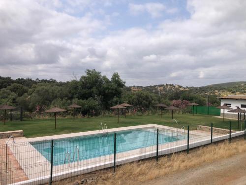 - une piscine avec des parasols et un terrain dans l'établissement Alojamiento Rural 'al Muniat', à El Castillo de las Guardas