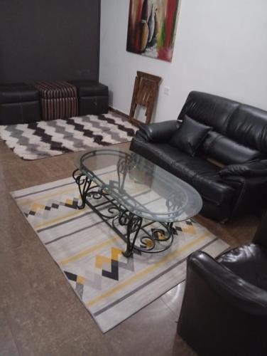 a living room with a glass table and a couch at The Bougainville Apartments in Asaba