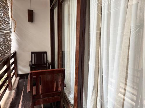 a room with a window with a chair and a television at Bayay ni Mamang Siargao - Ground Level in General Luna