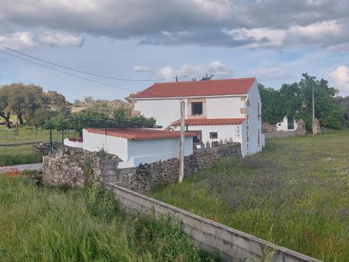 a white house with a stone wall in a field at Casa da Tartaruga - Marvão in Santo António das Areias