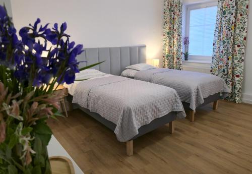 a room with two beds and a vase of flowers at Apartament Sikorskiego 65 in Kętrzyn