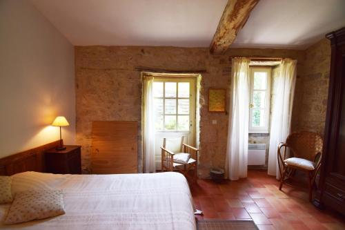 a bedroom with a bed and two windows at Maison en pierre à Laroque-Timbaut - Clévacances 3 clés in Laroque-Timbaut
