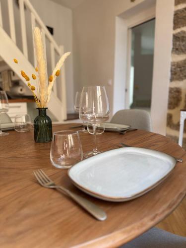 - une table en bois avec une assiette blanche et des verres à vin dans l'établissement ExVoto - Appartement de charme - Centre historique, à Pézenas