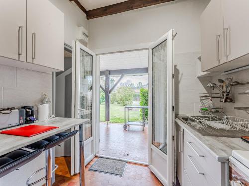 une cuisine avec des placards blancs et une porte donnant sur une cour. dans l'établissement Maison à Sanguinet pour 3 pers, 200m du lac, terrasse et jardin - FR-1-521-250, à Sanguinet