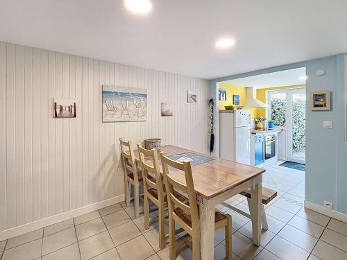 une cuisine et une salle à manger avec une table et des chaises en bois dans l'établissement Maison rénovée, à 300m de la plage et proche commerces, avec terrasse et jardin, tout confort - FR-1-361-131, à Saint-Pair-sur-Mer