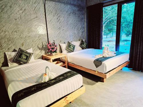 two beds in a room with a window at คีรีเขาสกริเวอร์ in Khao Sok