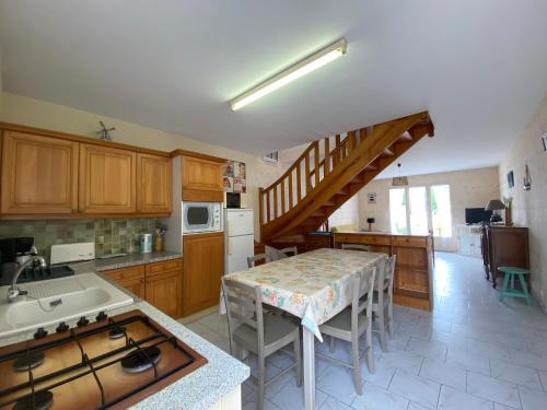 une cuisine avec une table et une cuisine avec un escalier dans l'établissement Maison rustique au centre-ville, proche plage, avec jardin et 3 chambres ! - FR-1-22-223, à La Tranche-sur-Mer