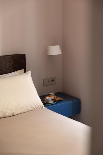 a bed with a blue end table with a plate of food at Freshwater Pirates SUITES in Gaeta