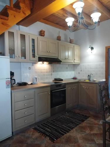 a kitchen with white cabinets and a black oven at Thalia's Cottage in Kámpos