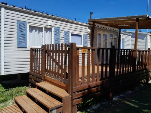 une maison avec une terrasse en bois devant elle dans l'établissement Mobilhome tout confort, à Port-la-Nouvelle