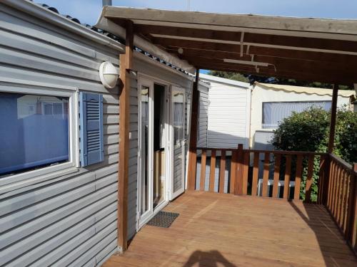 une terrasse couverte d'une maison avec une terrasse en bois dans l'établissement Mobilhome tout confort, à Port-la-Nouvelle