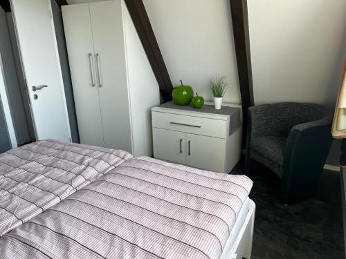 a bedroom with a bed and a dresser with a chair at Nurdachhaus mit Blick ins Grüne- ruhige Lage nahe Yachthafen Fedderwardersiel in Fedderwardersiel