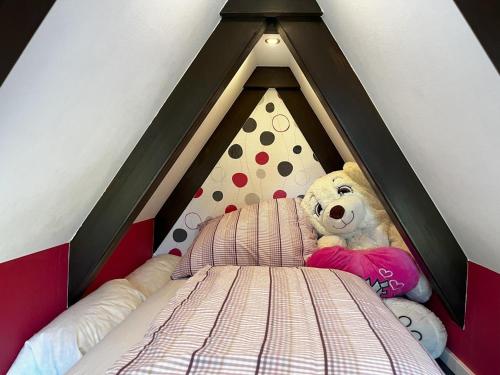 a teddy bear sitting in a bed in a room at Nurdachhaus mit Blick ins Grüne- ruhige Lage nahe Yachthafen Fedderwardersiel in Fedderwardersiel