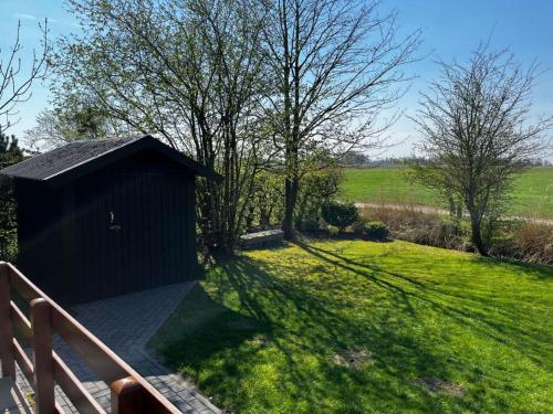 a small blackshed in a field of green grass at Nurdachhaus mit Blick ins Grüne- ruhige Lage nahe Yachthafen Fedderwardersiel in Fedderwardersiel
