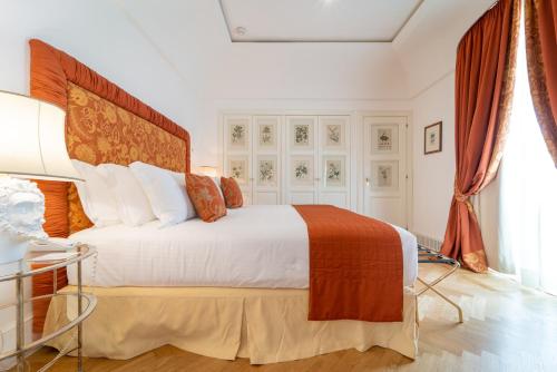 a bedroom with a large bed with white sheets and orange pillows at Relais Villa San Martino in Martina Franca