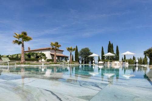 a large swimming pool with palm trees and umbrellas at Villa Delle Vigne in San Venanzo