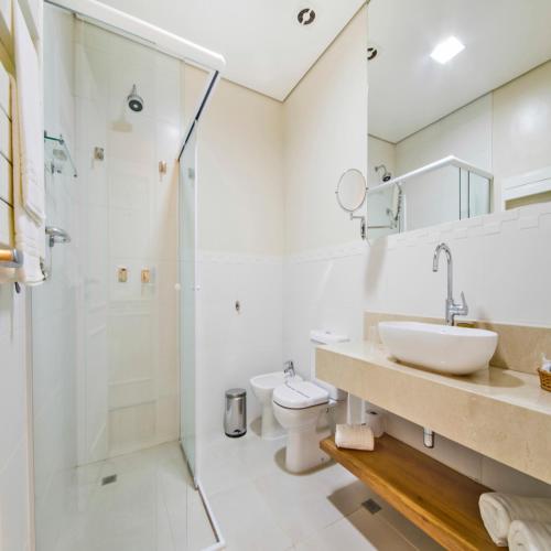 a bathroom with a shower and a sink and a toilet at Hotel Chateau in Campos do Jordão