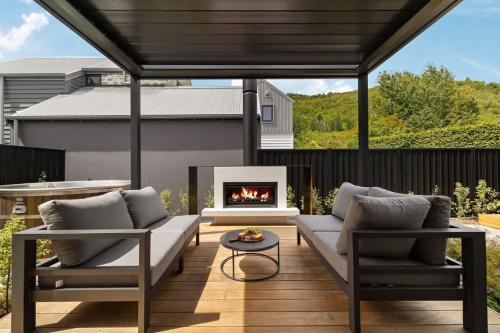 a patio with a couch and a fireplace at Cottonwood Villa in Arrowtown