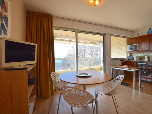 a living room with a table and chairs and a television at Appartement cozy au centre d'Évian pour 4 personnes - FR-1-498-58 in Évian-les-Bains